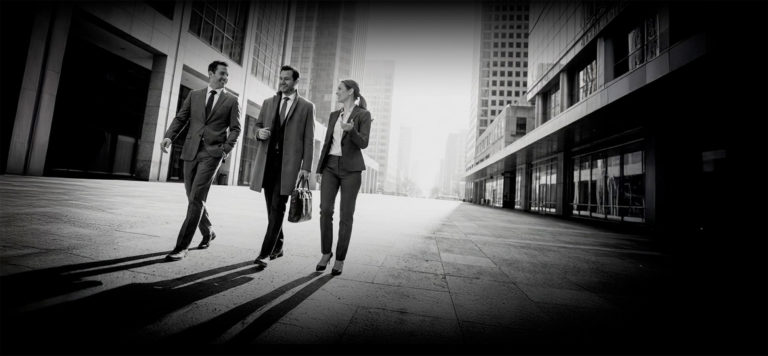 due uomini e una donna di affari che camminano in strada in mezzo ai grattacieli
